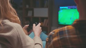 Couple of Gamers Playing Video Game on TV Screen with Console Controllers Close-up. Happy Man and Woman Have Fun at Home with Black and White Player Controls of PC. Two People Focused on Football