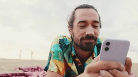 Close up, smiling man relaxing on the beach with smartphone in his hands - Powered by Shutterstock - Get 15% off with code: PIKWIZARD15