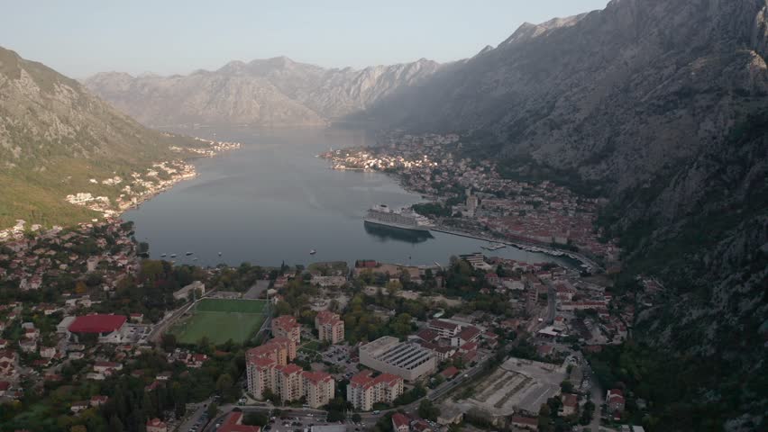 Aerial panoramic video of the picturesque bay of Kotor (Boka Kotor) with beautiful coastline, red roofs, marina with boats and big cruise ship, Montenegro