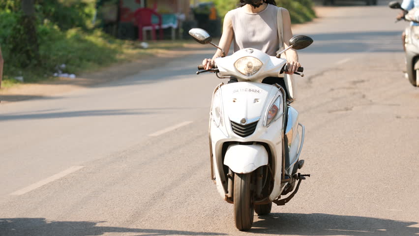 Rural indian woman rides two wheel motorbike. Female biker drives motorcycle. City road way traffic india. Girl motorcyclist fast move moto bike. Person went motor scooter trip. Moped rider close up.