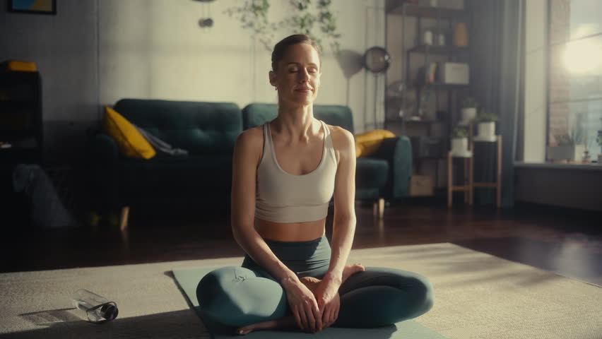 Beautiful Relaxed Caucasian Woman Meditating In Loft Apartment Living Room. Animated Visualization Of Bright Energy Accumulating In Her Chest. Yoga Practice, Self-care, And Mindfulness Concept. Royalty-Free Stock Footage #1103134223