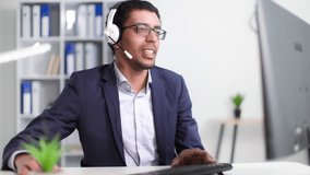 young black man works in technical support department in call center and advises client using headphones on microphone while sitting at office in office