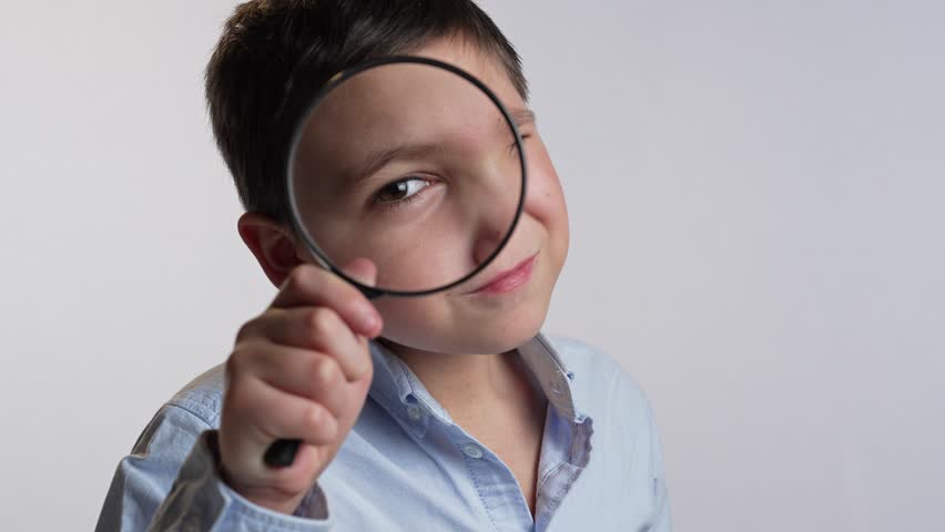 Boy looking through magnifying glass Royalty-Free Stock Footage #1103135167