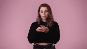 4k video of one girl using her phone over pink background.