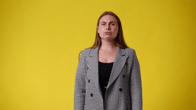 4k video of cute woman with negative facial expression on yellow background.