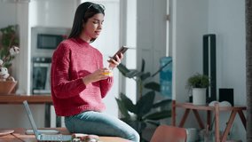 Video of beautiful young woman using smartphone while having healthy breakfast sitting on table at home