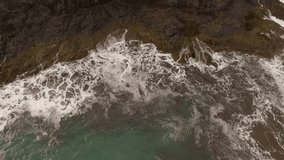 Ocean waves along a rocky coast. Slow motion seascape with epic rocks and waves crashing against the village. Cinematic drone shot of the landscape
