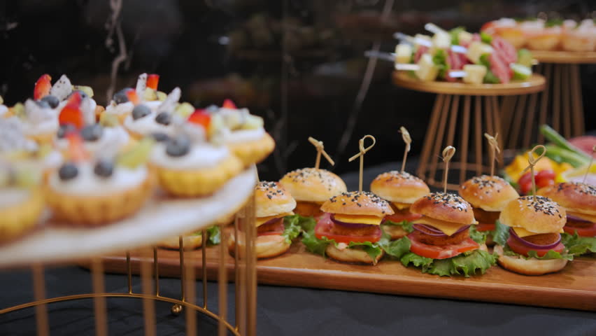Mini burgers on a wooden tray, snacks on the table, catering concept. Move camera Royalty-Free Stock Footage #1103141609
