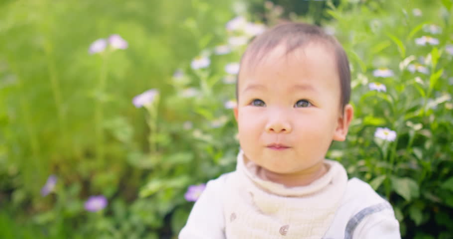 Adorable little Asian baby child toddler girl smiling looking at camera at garden outside home