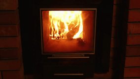 Close up stationary video of orange hot fire flame in fireplace. Wood plunks burning for the best heating. Central heating problem. Comfortable living and cozy atmosphere at country house