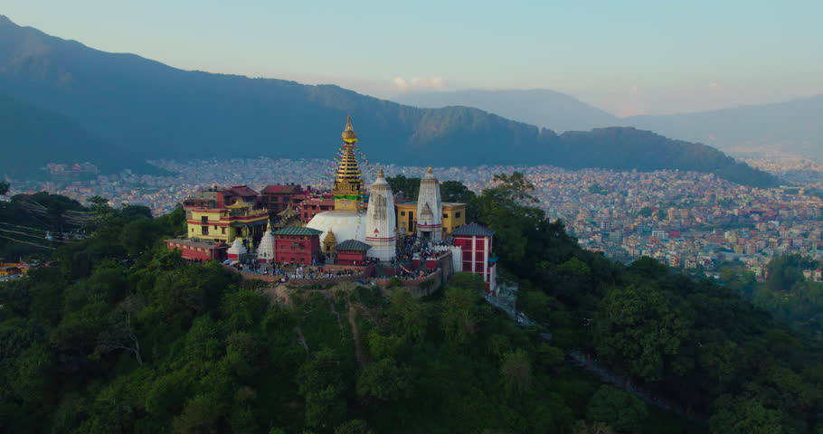 Orbiting Swayambhunath Stupa, Kathmandu at golden hour. The drone captures the intricate details of monkey temple while showcasing stunning sunset rays illuminating the city. Royalty-Free Stock Footage #1103144927