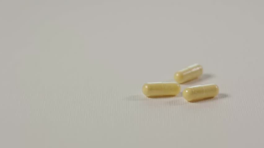 yellow medication tablet pills falling down on white clean pure surface in slow motion. Vitamin B complex Royalty-Free Stock Footage #1103157057