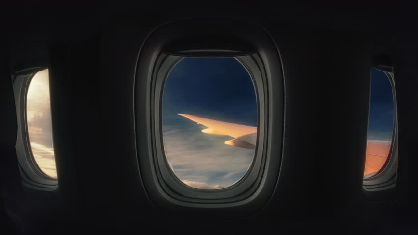 Airplane Porthole Sky Clouds Interior View Wings Travel Sunny Day. Window Interior view of an empty airplane flying through clouds during sunset Royalty-Free Stock Footage #1103160903