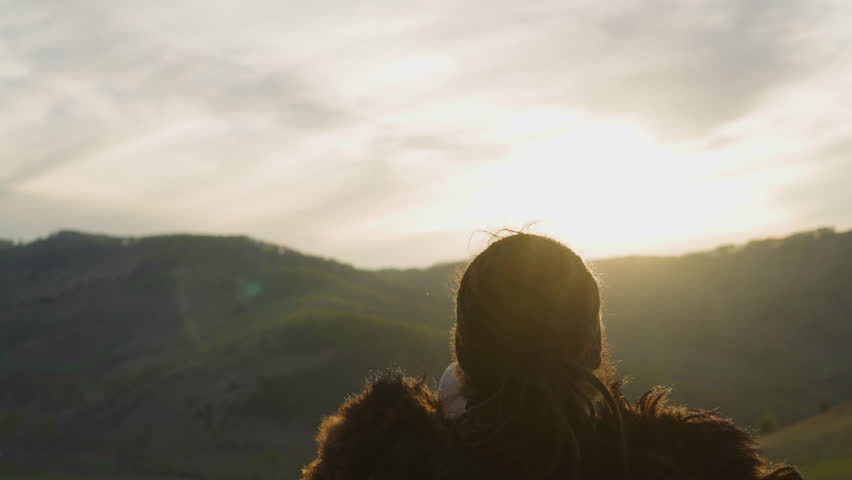 Silhouette of shaman playing ceremonial tambourine greeting new day at sunrise against mountains backside view. Siberian land mystical rituals Royalty-Free Stock Footage #1103163711