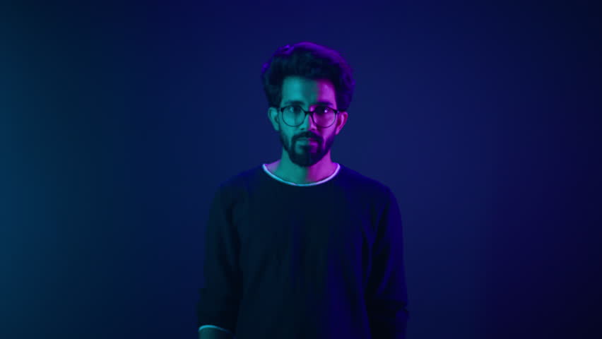 Studio dark blue neon background Indian man Arabian male model guy confused shrug shoulders unsure doubtful shrugging doubt uncertain don't know problem solution question guess puzzled bemused no clue Royalty-Free Stock Footage #1103164921