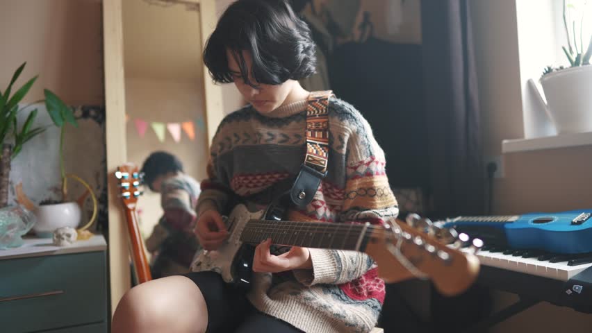 teenage girl plays electric guitar in her room. happy family music dreams concept. guitarist girl teenager. learning to play electric guitar at home. young female musician playing guitar lifestyle