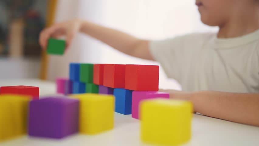 child girl in kindergarten play with blocks on table by the window. education development children game concept. child kid play with blocks at home rejoice having fun. child play cube at home Royalty-Free Stock Footage #1103168671