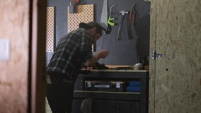 Adult Man Repairs Camera in Workshop, equipment hang on Black wall, Dolly revealing shot