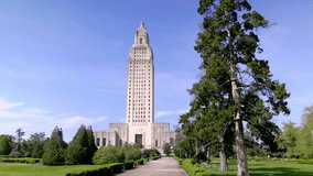 Louisiana state capitol building in Baton Rouge, Louisiana with gimbal video walking forward with big tree.