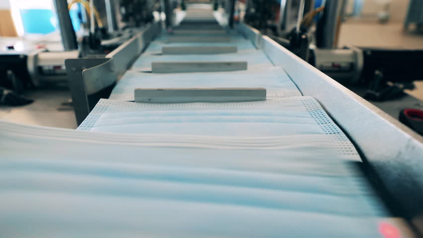 Conveyor belt with new medical masks on it in a close up