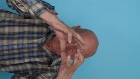cheerful caucasian grandfather shows a heart gesture with his hands, vertical video, blue background, studio shot.pensioner shows a sign of love