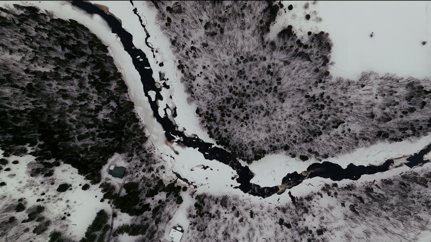 Aerial scenic cinematic drone straight down view pan Canadian wilderness mid winter near north Quebec Stoneham Ski Resort of frozen over Sautaurski River
