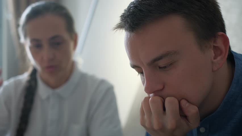 Mother expresses claims to an adult son sitting next to him on the couch. Family relationships, parenting