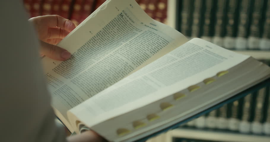 Close-up female hands holding and reading a book Holy Bible in public library. Theologian studies the history of the World. Search for truth. Royalty-Free Stock Footage #1103187189