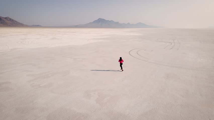 Aerial shot of an Asian woman jogging across the Bonneville Salt Flats flats in Utah
