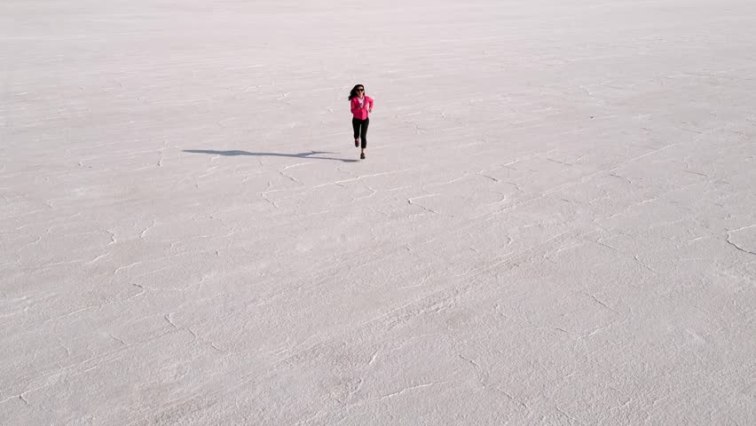 Aerial shot of an Asian woman jogging across the Bonneville Salt Flats flats in Utah