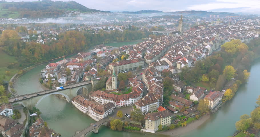 Aerial sunrise over Bern old town, the capital city of Switzerland with magical morning clouds and fog. Drone fly over Aare river Swiss historic cityscape landmark in autumn. Europe traveling concept.