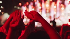 Close-up of a crowd at a music concert waving their hands, a red light falls on them. A scene with a lot of colourful lights in the background - Powered by Shutterstock - Get 15% off with code: PIKWIZARD15