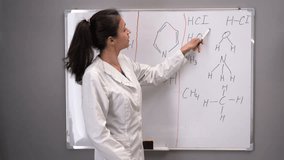 A teacher-blogger records a live training video, stands at a marker board and shows chemical formulas and their meaning. chemistry lesson online. Blog concept. webcam view.