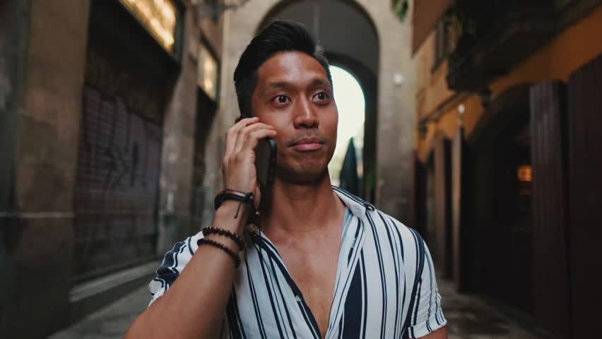 Young man tourist walks along narrow street of the old city and talks on mobile phone