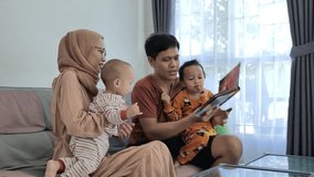 A family with two children reading a book together in the living room, side shot - Powered by Shutterstock - Get 15% off with code: PIKWIZARD15