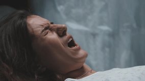 Female patient on operating table in hospital screaming in pain. Portrait of pregnant woman in labor in maternity ward, nurse wipes sweat from forehead - Powered by Shutterstock - Get 15% off with code: PIKWIZARD15