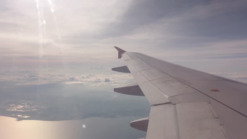 view of sky from inside airplane cabin while flying over cloud sky scape through the window with wing view in daytime Royalty-Free Stock Footage #1103209495