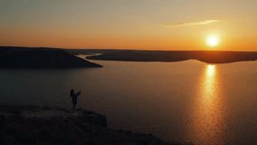 Cinematic shot of a young woman filming on a smartphone camera at sunset with an incredible view, or a blogger recording a video about her trip
