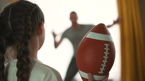 Father's day. Child with his father play with rugby ball. Joy of child playing ball with his father at home. Child's face lights up with excitement. Family home game. Father encourages the child. - Powered by Shutterstock - Get 15% off with code: PIKWIZARD15