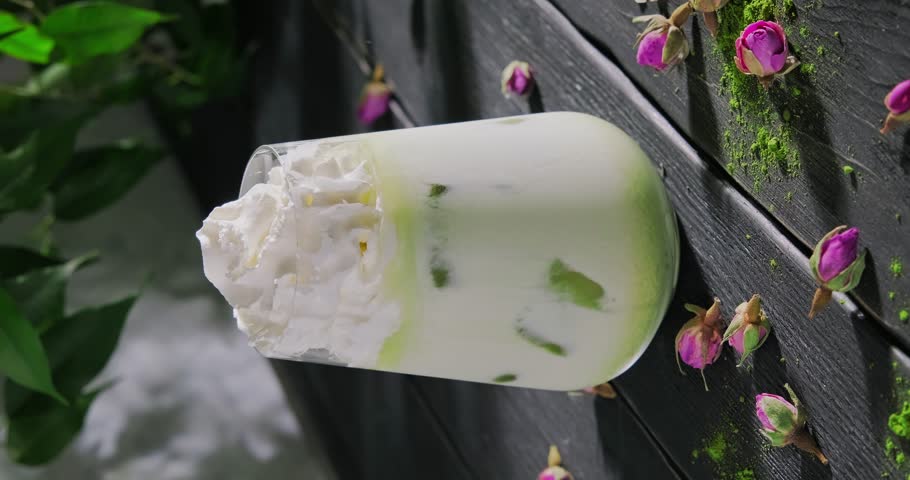 Preparing matcha latte drink wih milk and ice cubed, sprinkling green powdered matcha over milk froth,, high quality vertical video clip, 4k footage | Shutterstock HD Video #1103215885