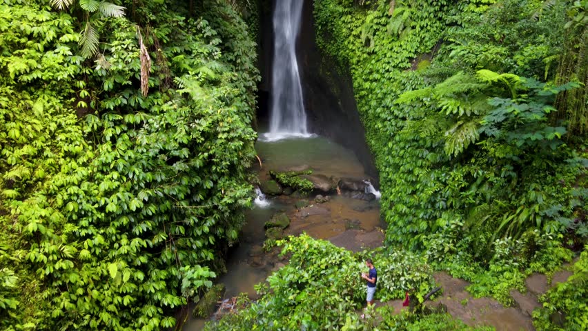 Epic cinematic aerial view of the Leke Leke Waterfall in Tabanan Regency in Bali, Indonesia. hidden Paradise deep in the jungle. Forward tilt up reveal shot .