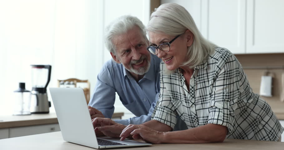 Happy older couple talking, using laptop, doing online shopping, discussing on-line news, web surfing information, making order, booking hotel, browse website, feel satisfied using electronic services Royalty-Free Stock Footage #1103218565