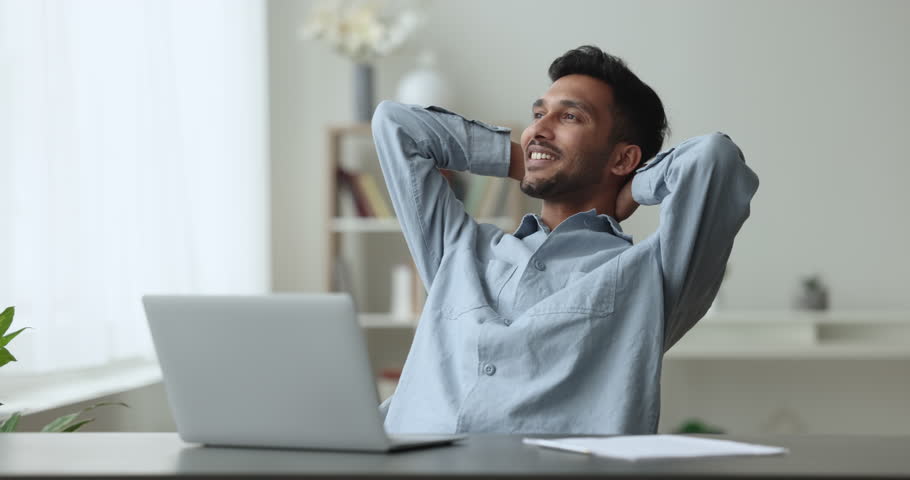 Indian man employee finished work leaned on chair with hands behind head, enjoy break, fresh conditioned air inside office room at summer day. Stress-free workday, successful accomplishment of project Royalty-Free Stock Footage #1103218677