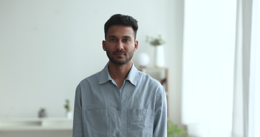 Happy Indian man in casual shirt posing with arms crossed in cozy living room, smiling looking at camera enjoy day off, carefree pastime alone at modern own dwelling. Portrait of homeowner or tenant Royalty-Free Stock Footage #1103218747