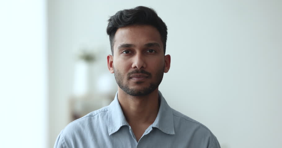Head shot handsome positive Indian man poses indoor. Millennial bearded guy with attractive appearance, wide toothed smile look at camera, tenant or homeowner, professional occupation person portrait Royalty-Free Stock Footage #1103218757