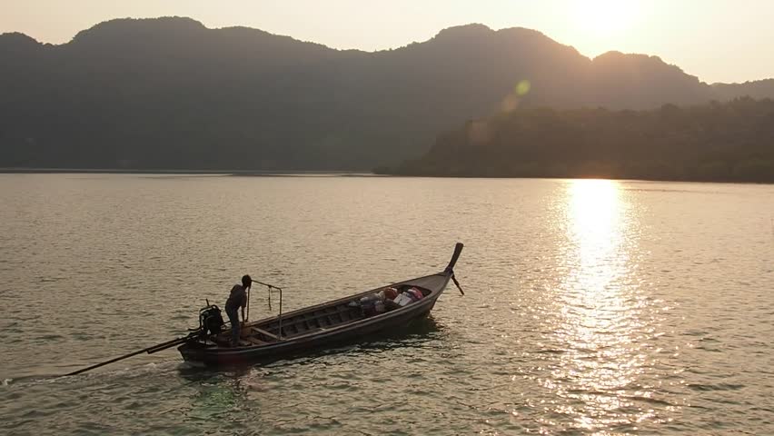 Sunset on the river, boat floats down the river to the sea ready to fish or return home late at night The sun splashes golden light, reflecting the beautiful waves.