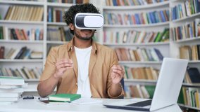 Young university teacher using virtual reality glasses for video call and online chat in virtual reality simulator, in campus library space. Tutor, coach has a remote meeting, virtual conference