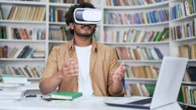 Young university teacher using virtual reality glasses for video call and online chat in virtual reality simulator, in campus library space. Tutor, coach has a remote meeting, virtual conference - Powered by Shutterstock - Get 15% off with code: PIKWIZARD15