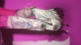 Women's hands in gloves with a dollar and a lot of clocks on the river on a pink background. Glamorous stylish video shooting.