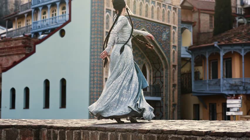 A beautifull woman in a national Georgian dress is dancing in Old Tbilisi city .  Royalty-Free Stock Footage #1103227491
